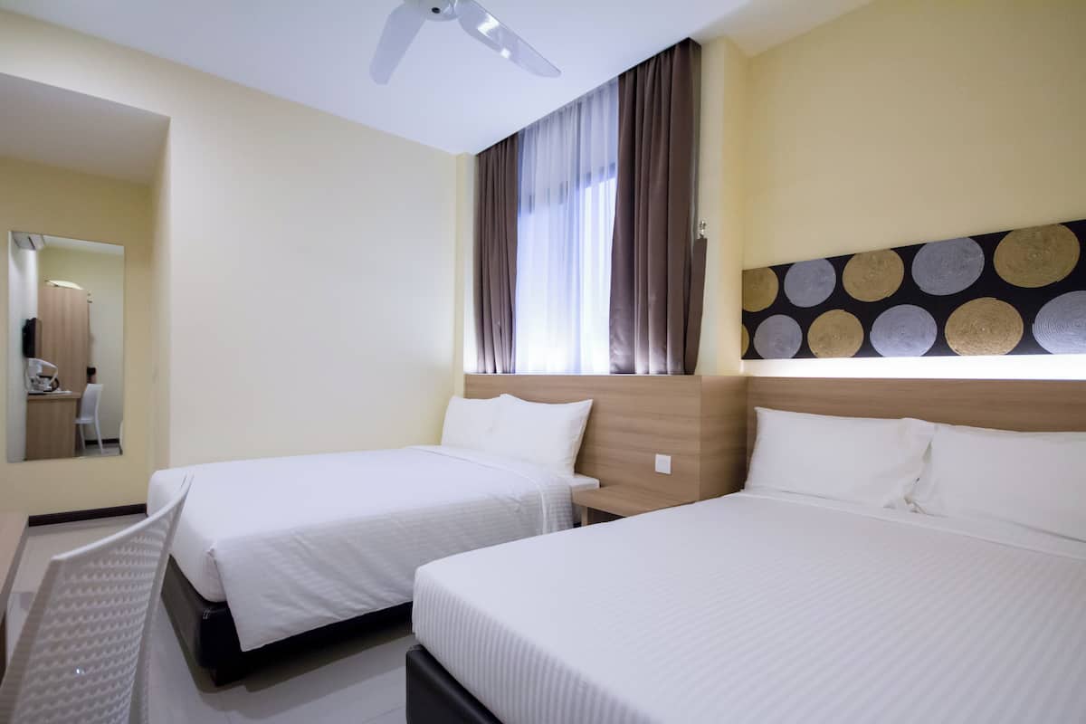 A hotel room with two beds, a ceiling fan, a mirror, and a window with curtains.
