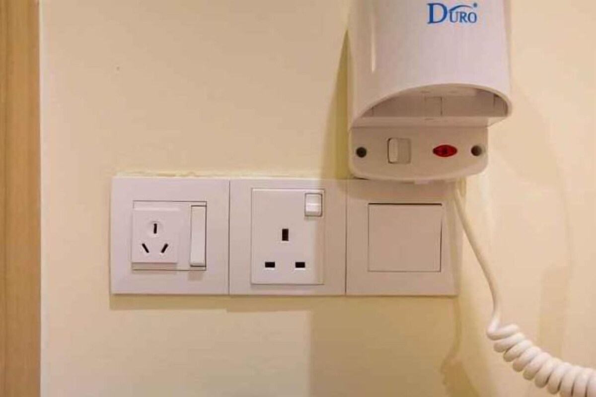 A wall-mounted power outlet with a white corded telephone and a Duro plug.
