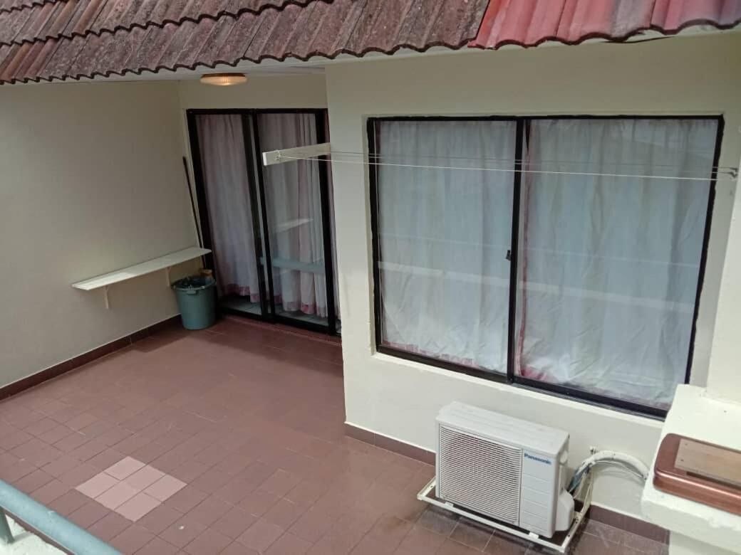 A balcony with a tiled floor, a white air conditioning unit, and a window with a curtain.