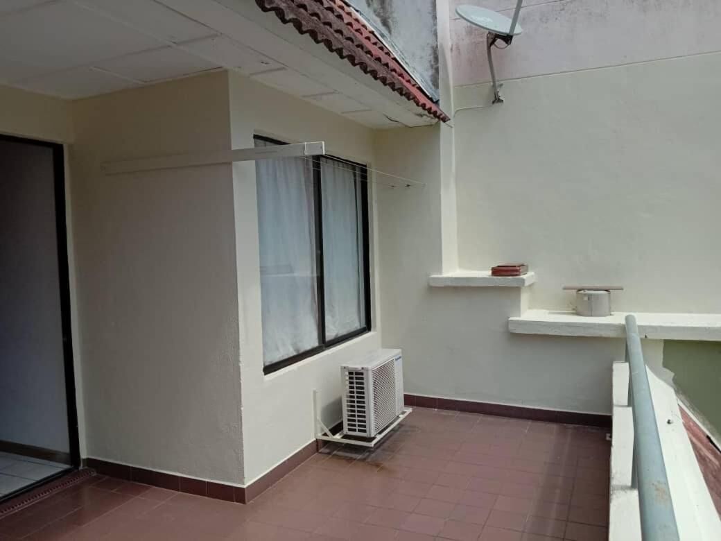 A small balcony with a white air conditioning unit, a window with a curtain, and a satellite dish on the wall.