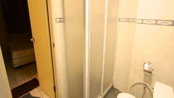 A bathroom with a toilet, a shower enclosure, and a sink.