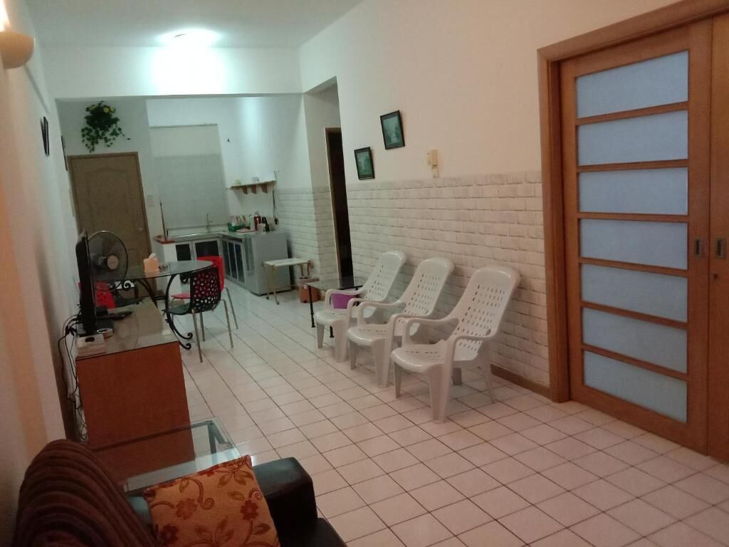 A room with a tiled floor, a wooden door with frosted glass panels, and a seating area with white plastic chairs.