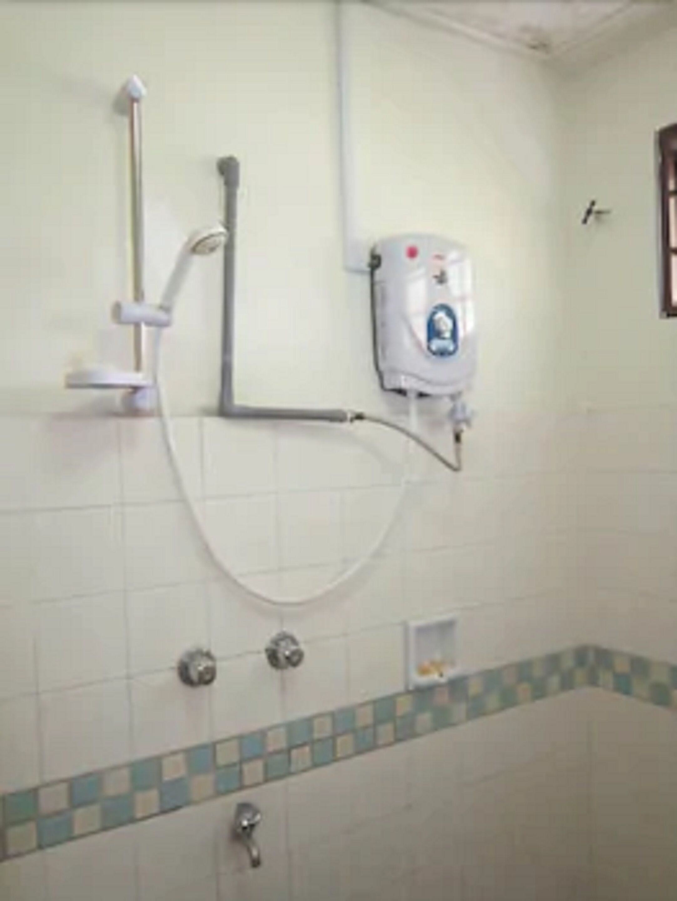 Casa de banho com chuveiro, dispensador de sabonete e chão em mosaico.