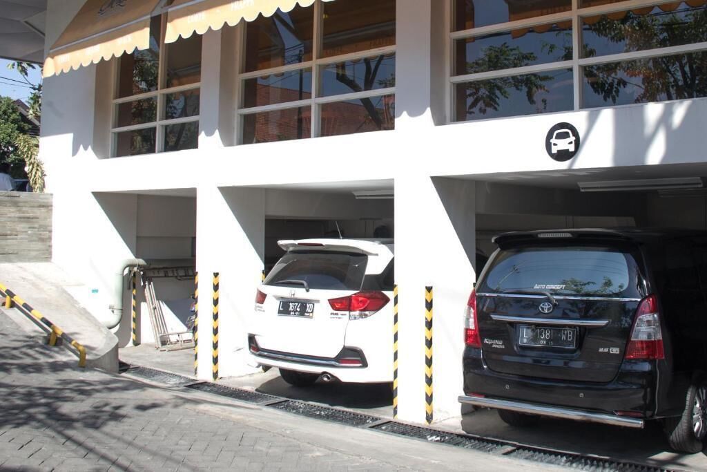 A building with a car parking area, including a white Honda and a black Toyota SUV.