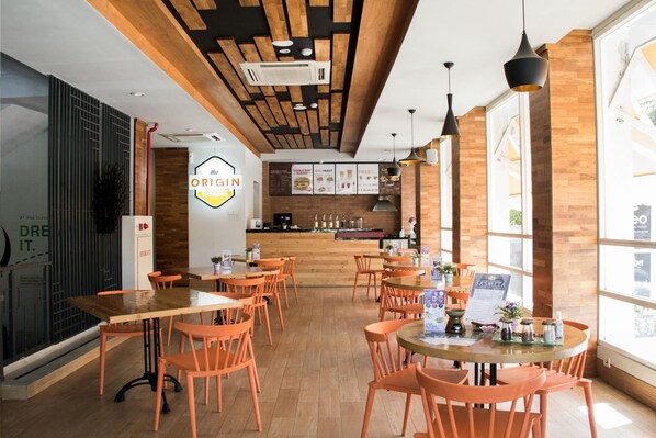 A restaurant interior with wooden tables and orange chairs, a kitchen area, and a menu board. - Cleo Business Hotel Walikota Mustajab City Center (Surabaya)