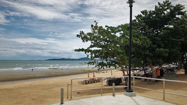 A beach with a concrete walkway, a metal railing, and a street lamp. - Baan Talay (Pattaya)