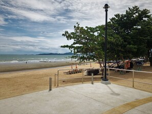 A beach with a concrete walkway, a metal railing, and a street lamp. - Baan Talay (Pattaya)