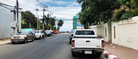 A street scene with parked cars, a white pickup truck, and a building with a sign.