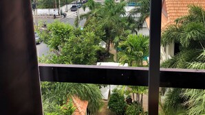 A view from a window overlooking a beach, palm trees, and a building with a sign advertising 'Sands'. - Baan Talay (Pattaya)
