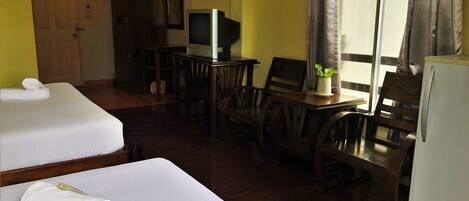 A hotel room with two beds, a television, a desk, and a refrigerator.