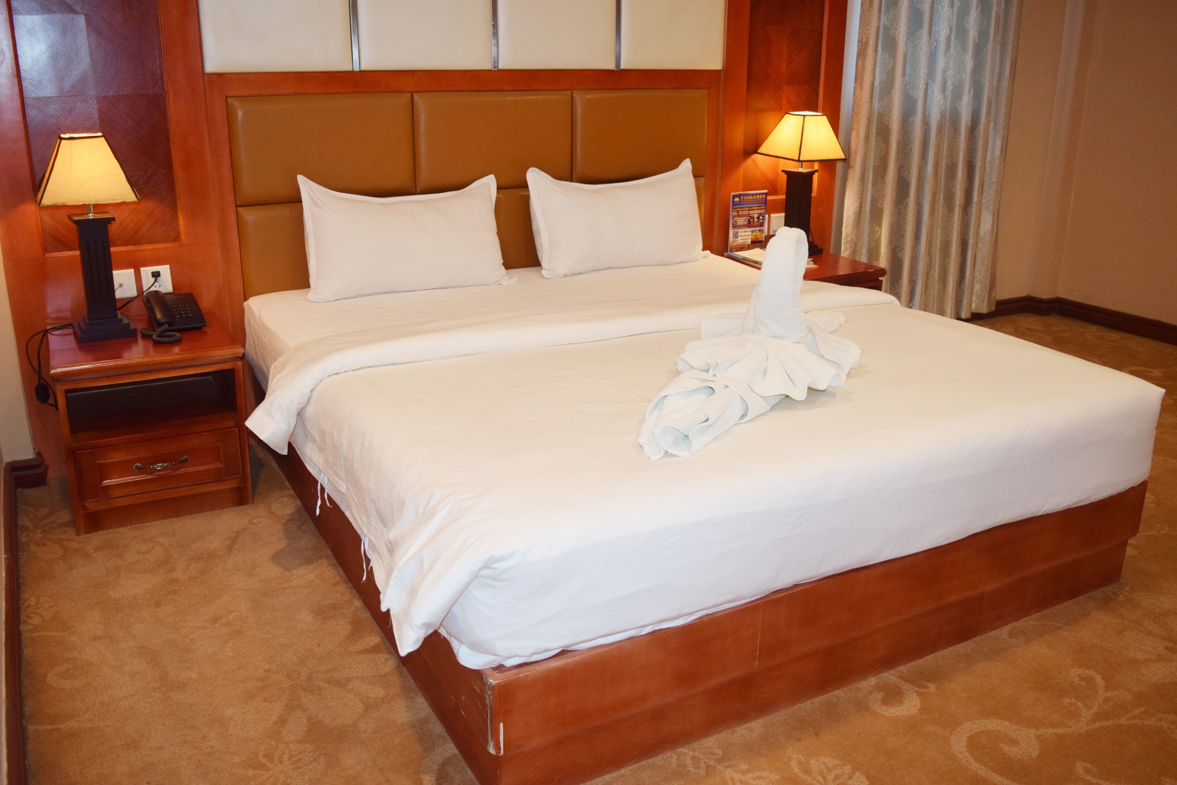 A double bed with white linens, two bedside tables with lamps, and a wooden headboard.