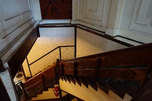 A grand staircase with ornate railings and a fire extinguisher at the bottom.