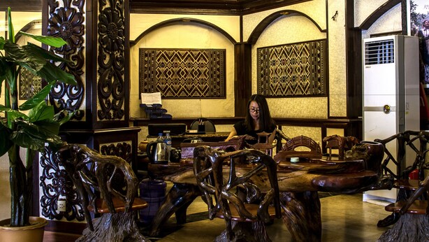 A restaurant with wooden furniture and decorative wall panels. - Dansavanh Vientiane Hotel (Vientiane)
