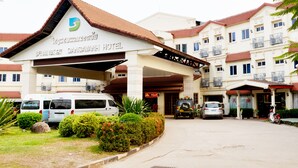 The entrance to Dansavanh Hotel with a covered walkway, multiple parked vehicles, and a well-maintained garden area. - Dansavanh Vientiane Hotel (Vientiane)