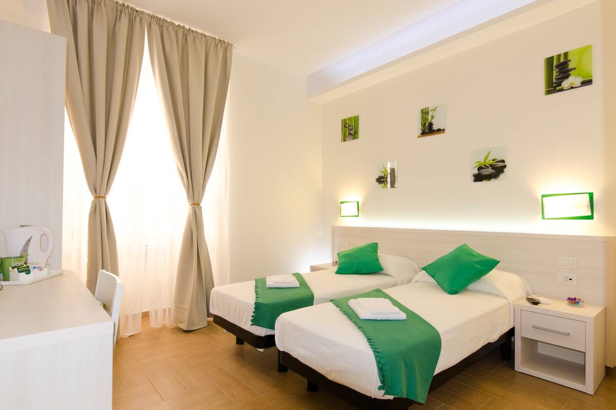 A hotel room with two beds, a desk, and a nightstand.
