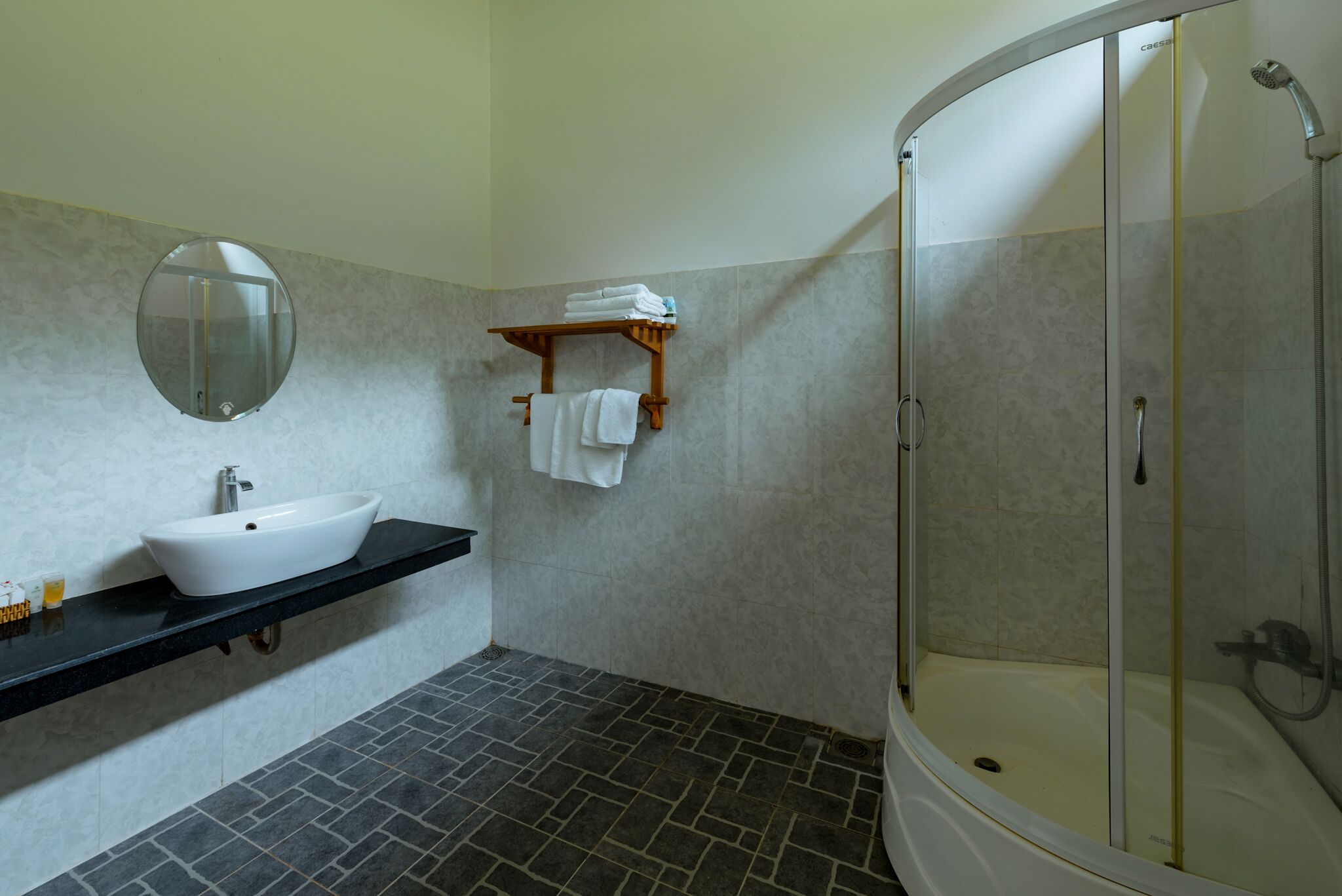 A bathroom with a white sink, a mirror, a towel rack, and a shower enclosure.