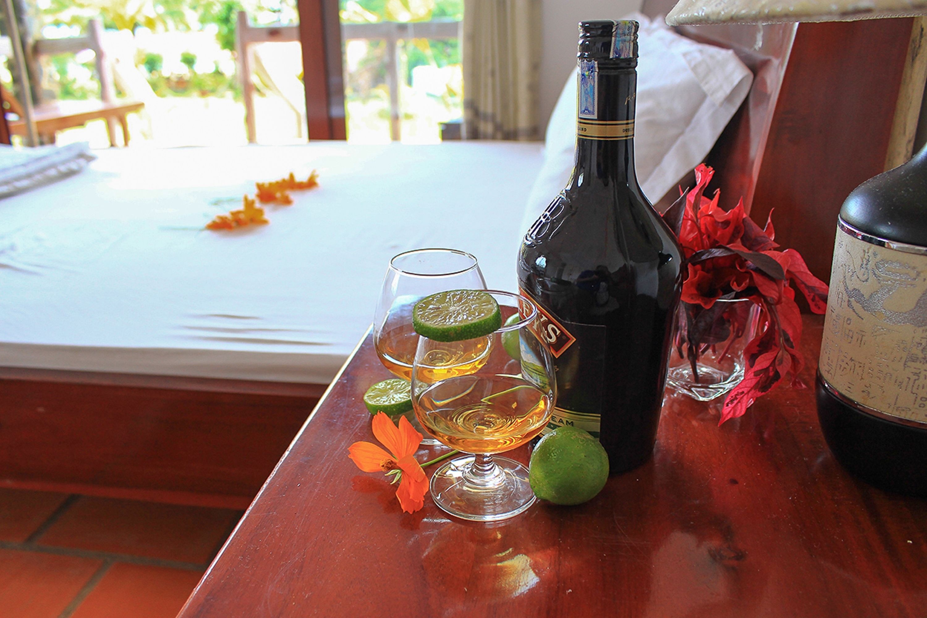 Una mesa de madera con una botella de vino, copas y gajos de lima.
