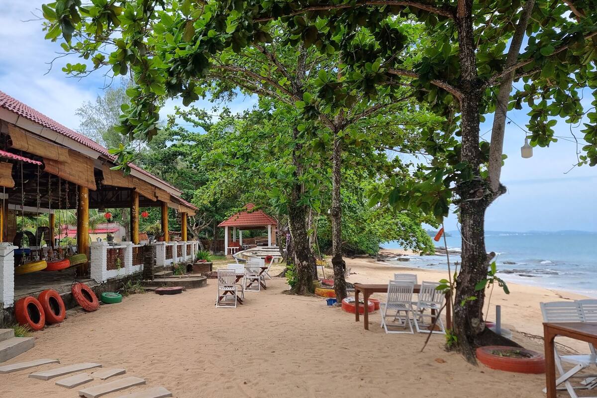 Ein Restaurant direkt am Strand mit Außenbereich, einer Laube und Meerblick.
