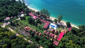 An aerial view of a coastal area with multiple buildings, a beach, and dense greenery. - Vung Bau Resort (Phu Quoc)