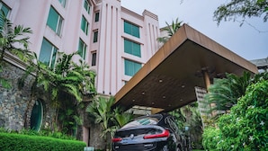 Un BMW X4 noir est garé devant un bâtiment rose à la façade en pierre et aux encadrements de fenêtres verts.