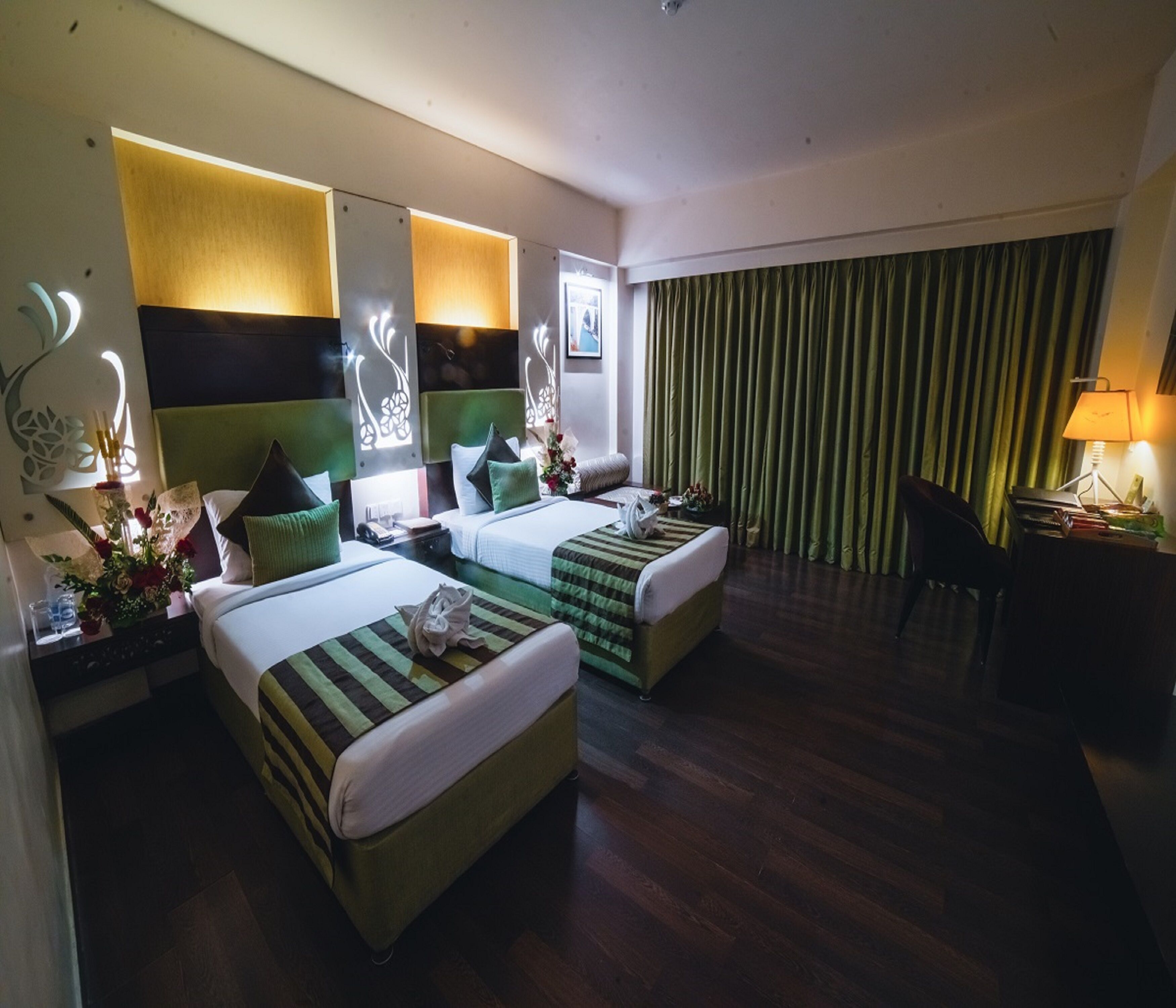 A hotel room with two beds, a desk, and a chair.