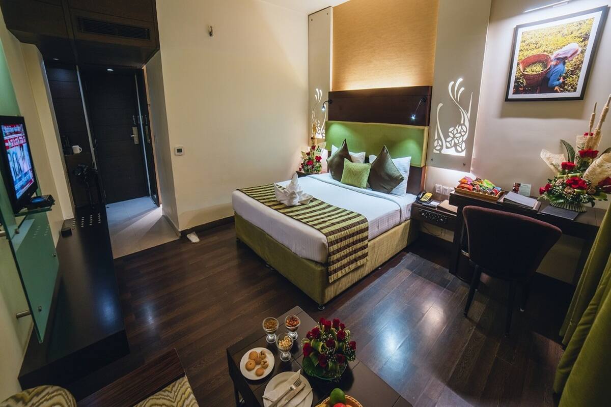 Une chambre d’hôtel comprenant un lit, un bureau, une chaise, une table à manger avec des articles pour le petit-déjeuner et un téléviseur.