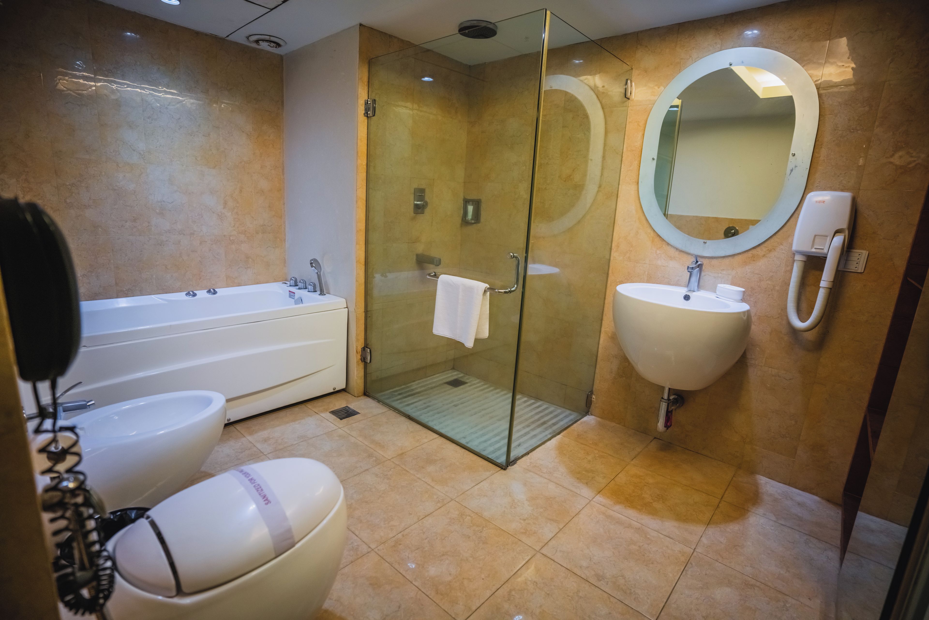 A modern bathroom with a bathtub, two sinks, and a glass-enclosed shower.