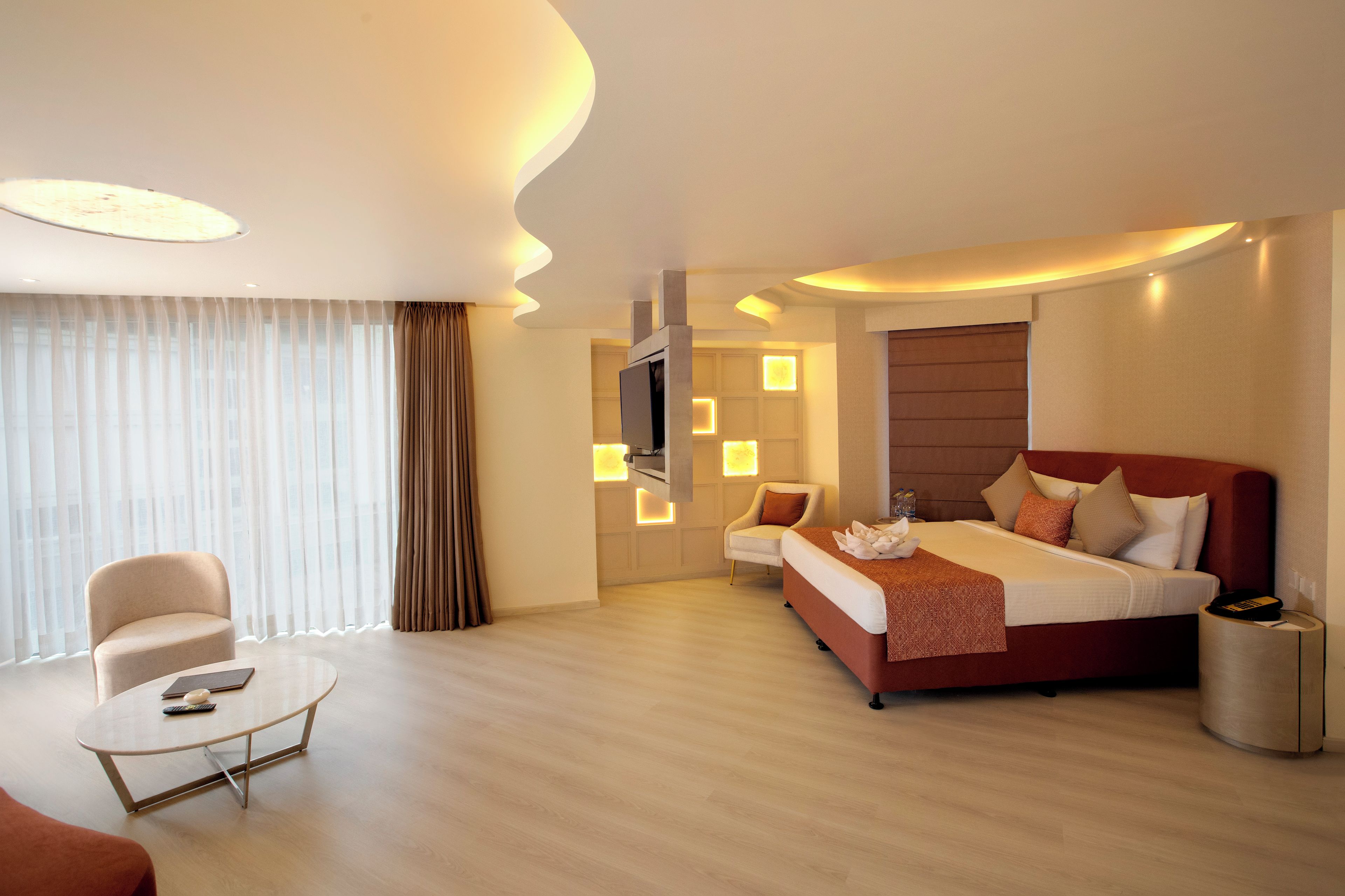 A hotel room with a bed, a chair, a small table, and a TV.