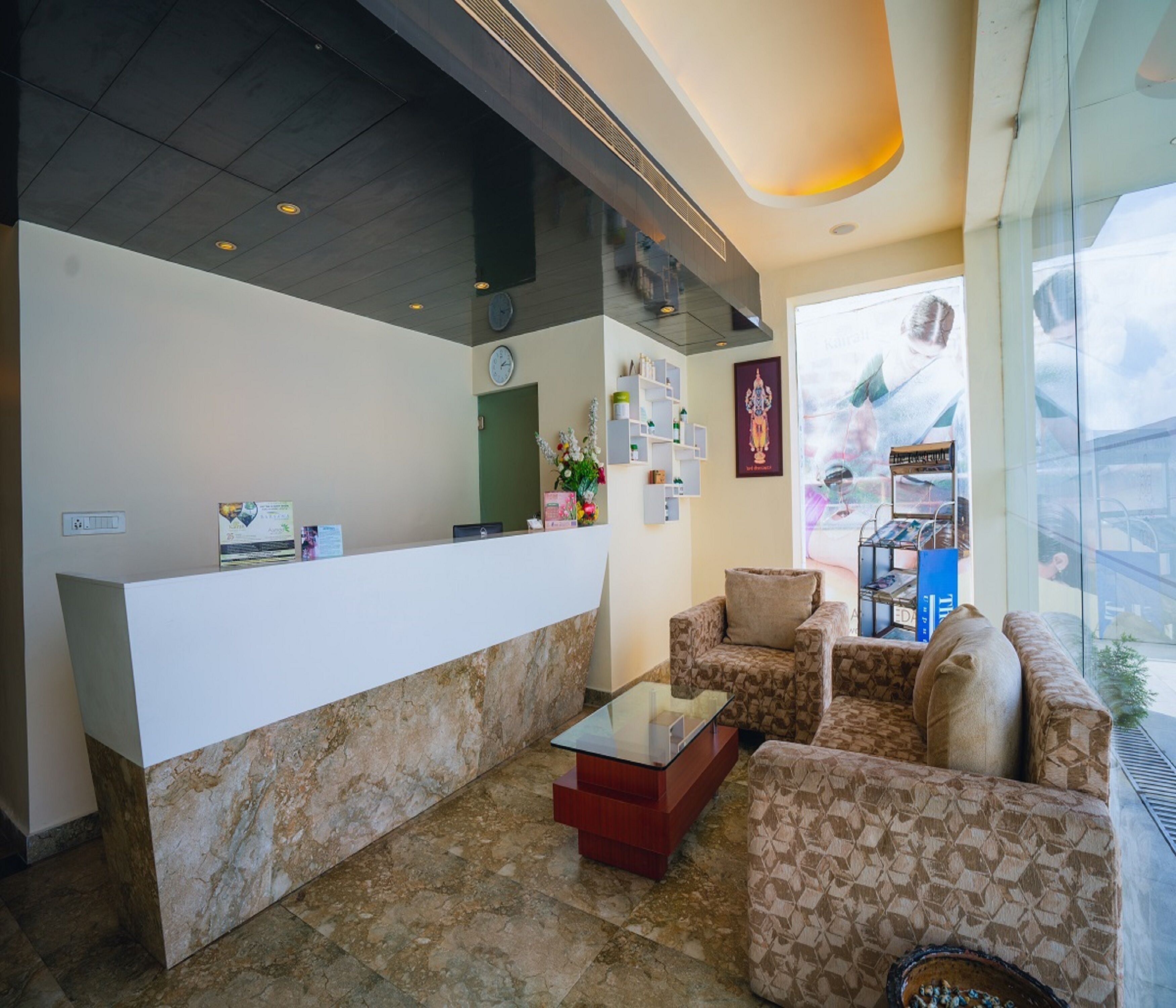 A reception area with a marble reception desk, patterned sofas, a glass coffee table, and a view through large windows.