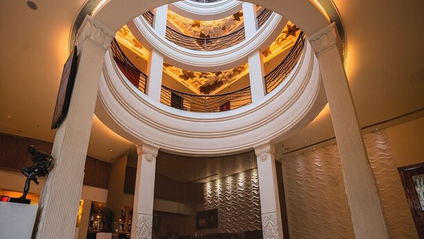 Un vaste atrium à plusieurs niveaux, doté d’un escalier central, d’élégantes colonnes et d’un lustre.