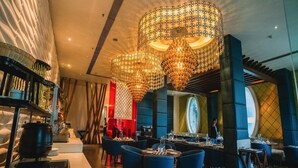 Un restaurant moderne avec de hauts plafonds, de grands lustres et un bar central.