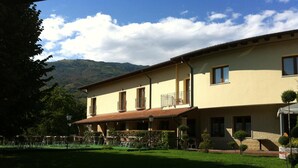 Un bâtiment à deux étages, doté d’un toit plat, de plusieurs balcons et d’un patio aménagé avec des sièges extérieurs.