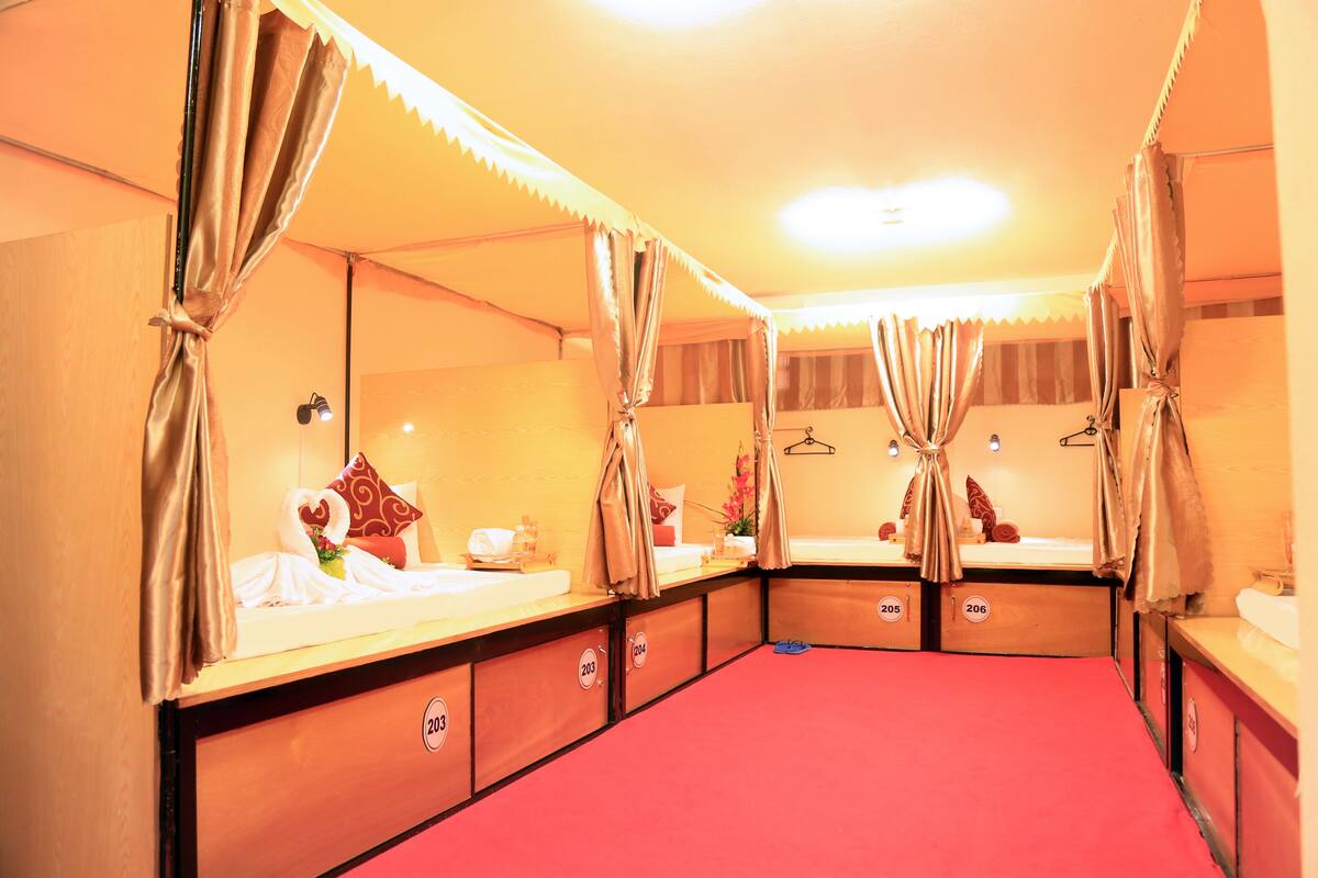 Ein Hotelzimmer mit vier Betten, jedes mit einer Nummer an der Seite, und einem roten Teppich.