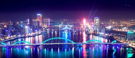 A nighttime cityscape with illuminated bridges and buildings reflecting on the water.