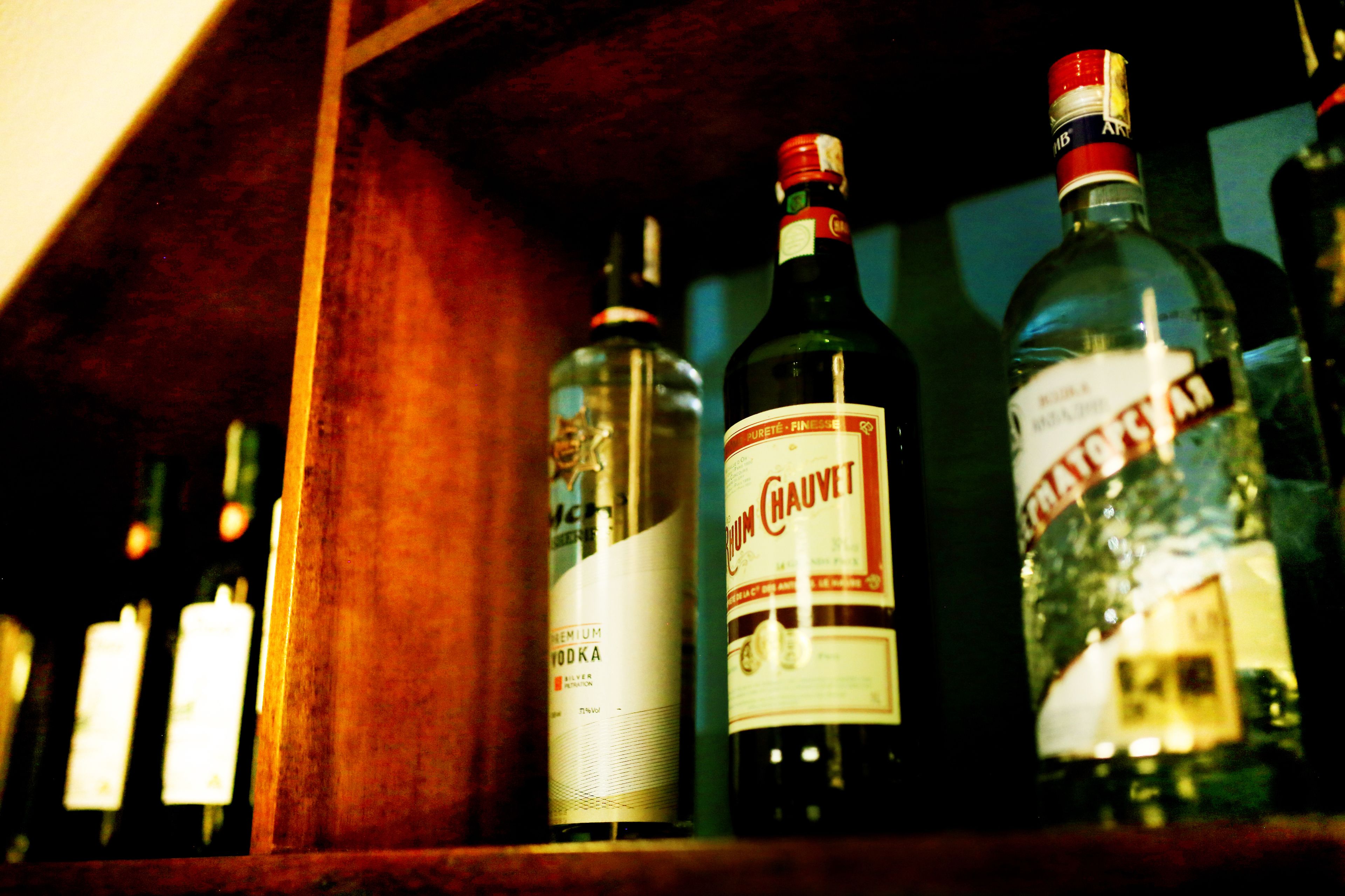 Una estantería con varias botellas de alcohol, incluyendo una botella destacada que dice "Premium Eau de Parfum".
