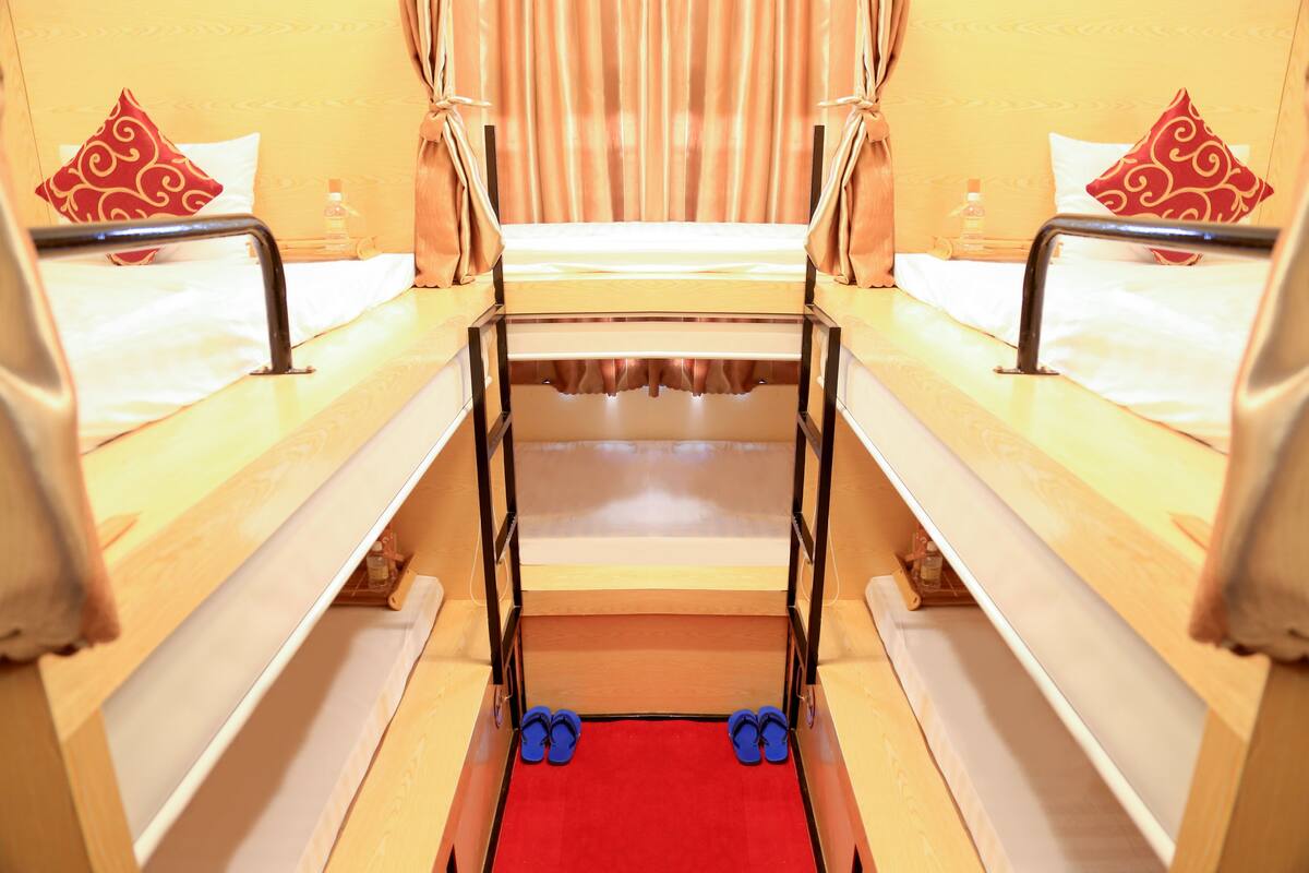 Ein Hotelzimmer mit zwei Einzelbetten, einem kleinen Tisch und einer Bank.