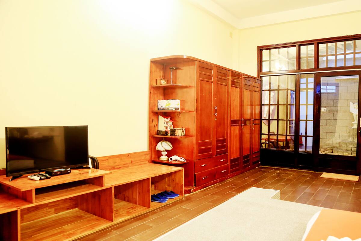 Ein Zimmer mit Fernseher auf einem Holzboden, einem Kleiderschrank und einer Bank.