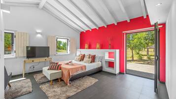 Un dormitorio moderno con cama, televisor y un ventanal grande.
