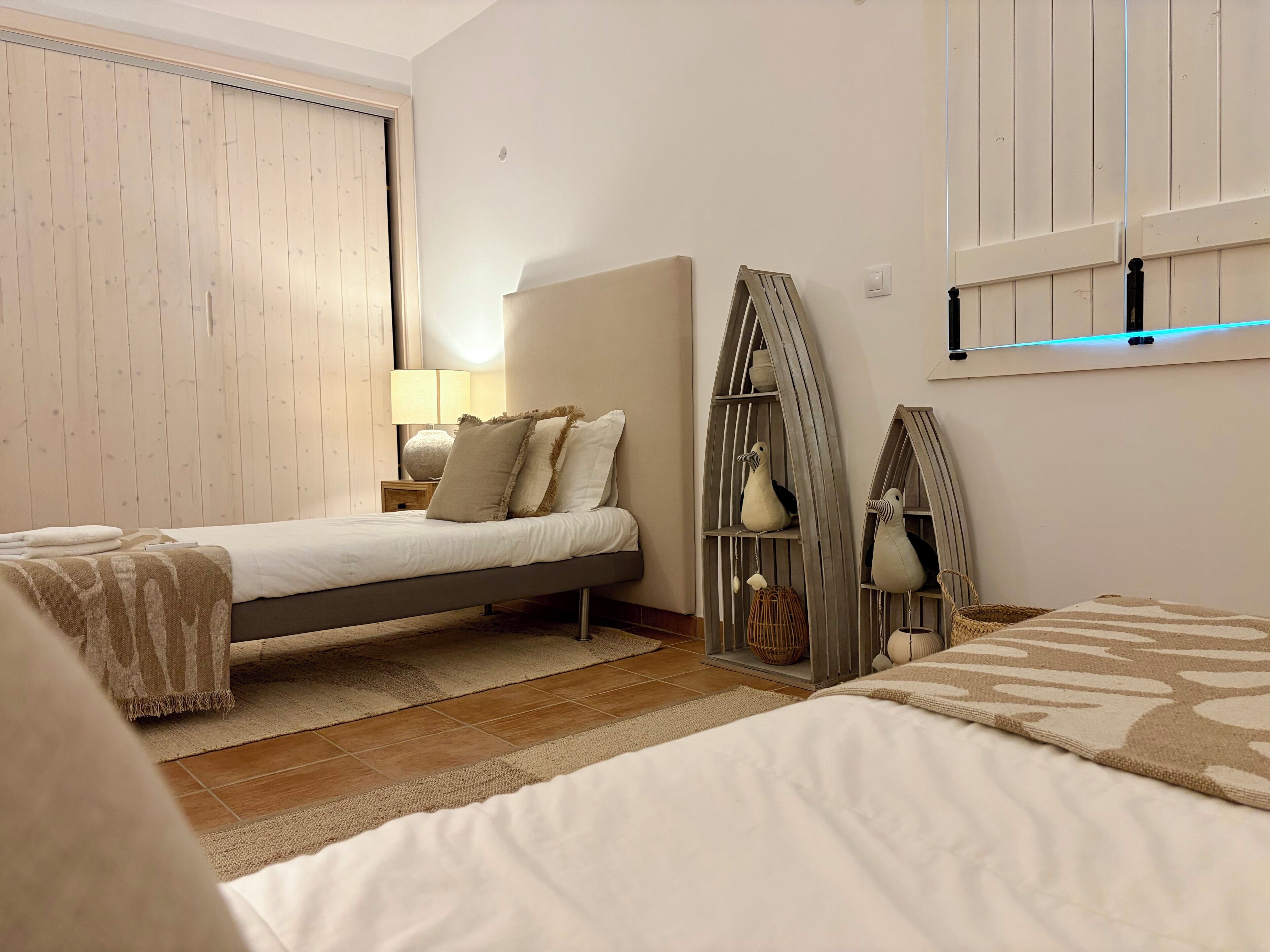A bedroom with a bed, bedside table, lamp, and decorative items.