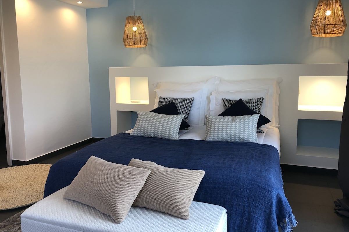 A modern bedroom with a large bed, two bedside lamps, and a headboard with built-in lighting.