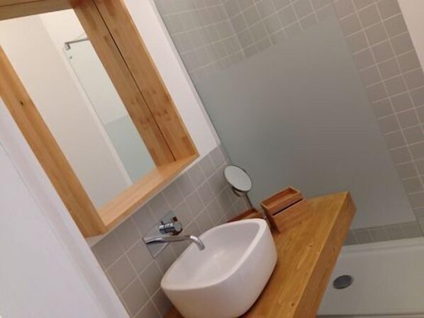 A bathroom with a wooden vanity, a white sink, and a mirror. - Tons da Terra (Santiago do Cacém)