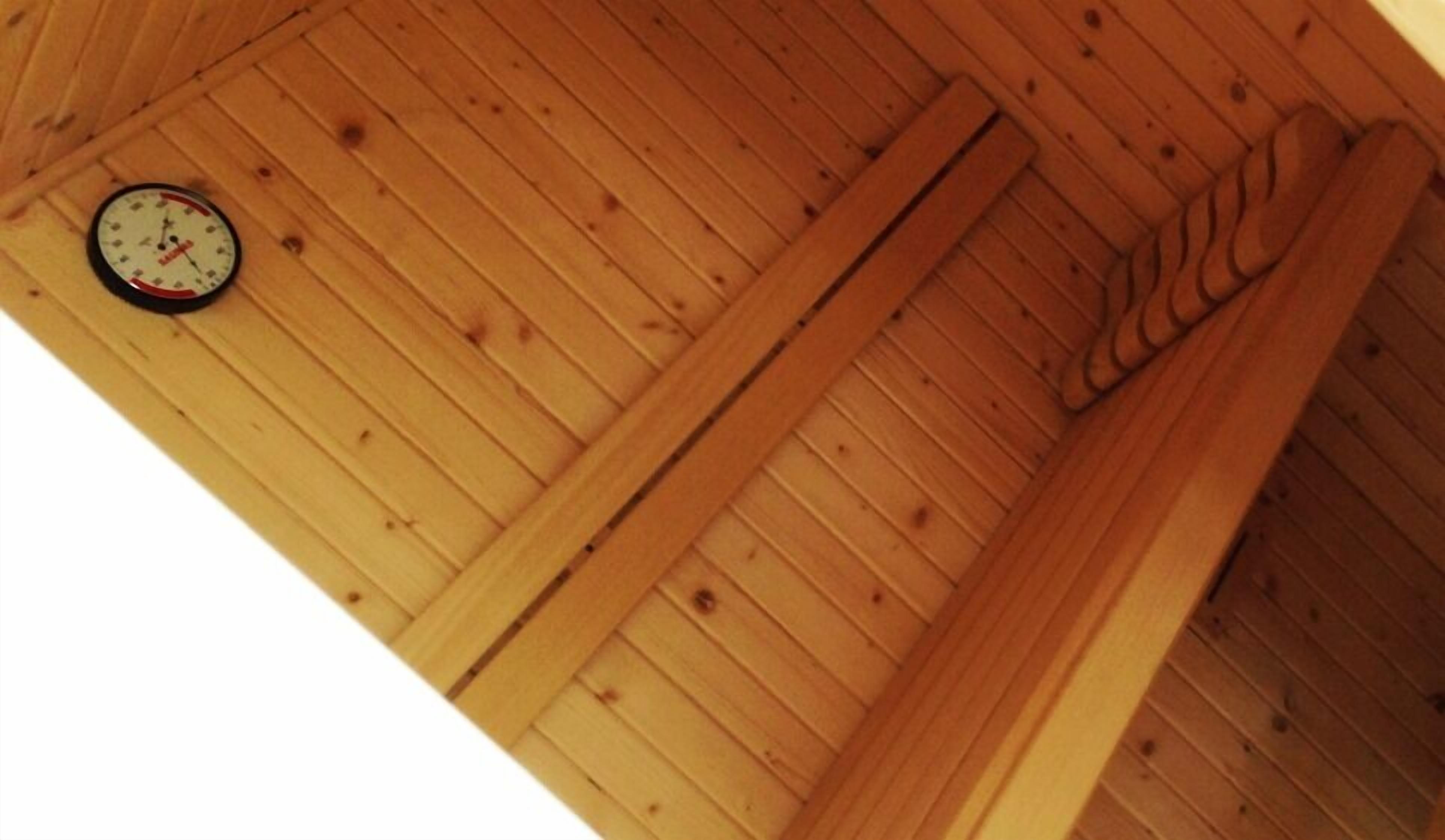 Techo de madera con un reloj montado en la pared y estructura de vigas de madera.