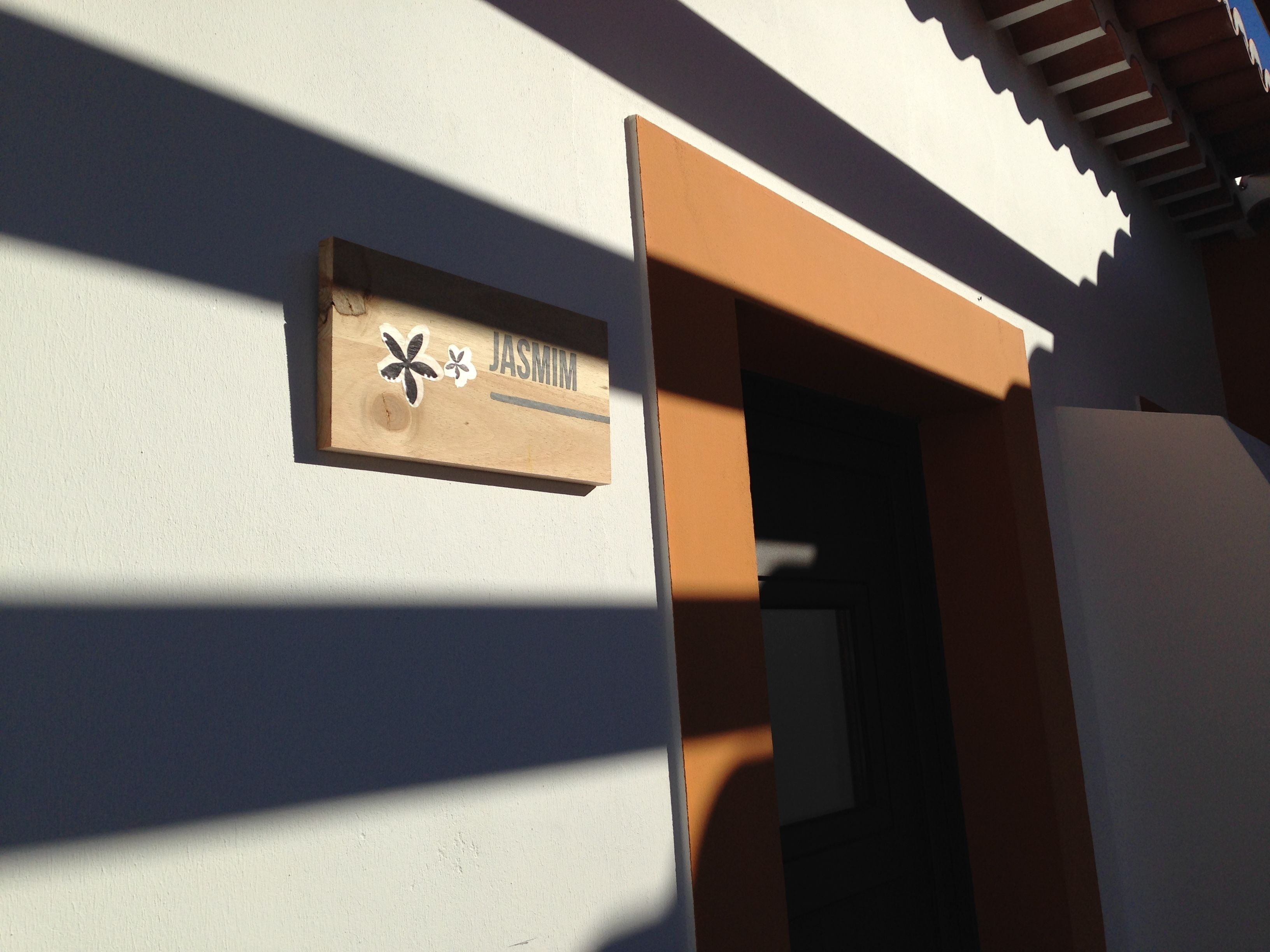 A wooden sign with the name "JASMIN" on a building's exterior wall.
