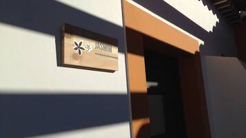 A wooden sign with the name "JASMIN" on a building's exterior wall.