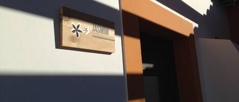 A wooden sign with the name "JASMIN" on a building's exterior wall.