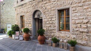 The exterior of the Termes Santa Agnese Hotel, featuring stone walls, large potted plants, and a traditional entrance with a fanlight. - Hotel Delle Terme Santa Agnese (Bagno di Romagna)