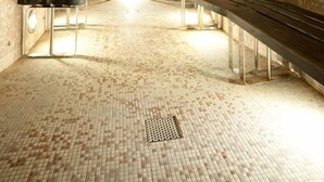 A sauna with benches and a tiled floor, a door, and a stone archway. - Hotel Delle Terme Santa Agnese (Bagno di Romagna)