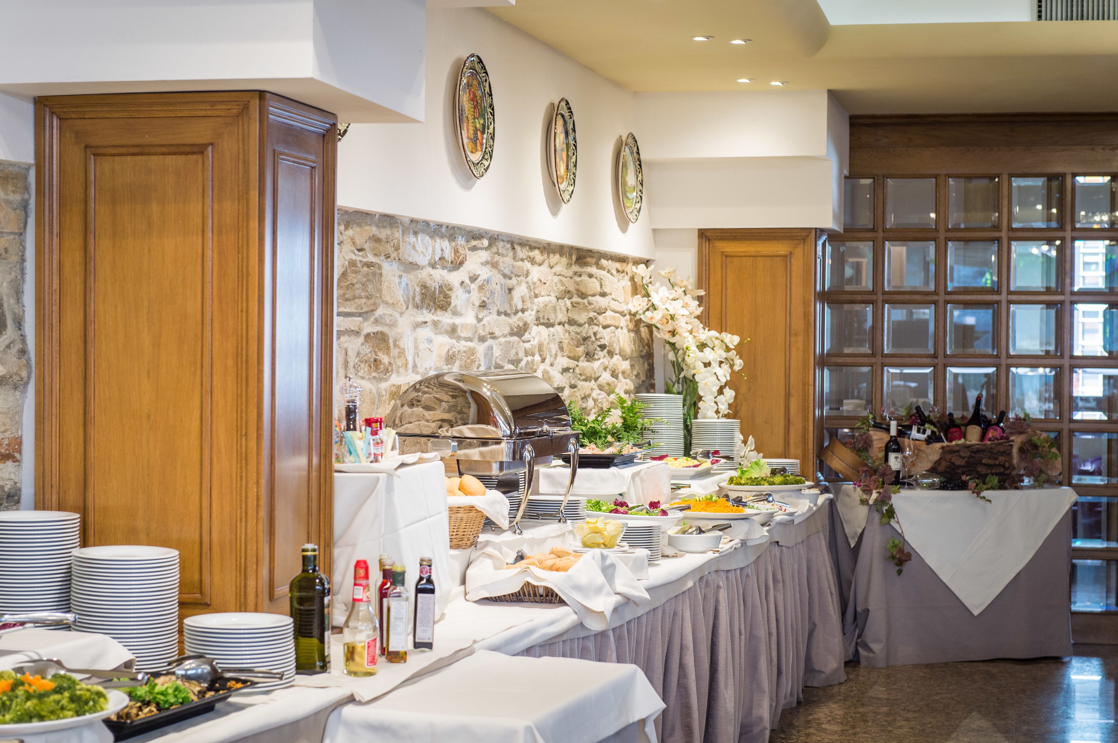 Un'area buffet con diversi piatti, una parete in pietra e vista all'esterno tramite ampie finestre.