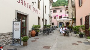 A courtyard with outdoor seating, a sign for 'Santa Agnese', and a bike parked nearby. - Hotel Delle Terme Santa Agnese (Bagno di Romagna)