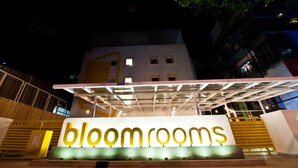 En bygning med et skilt, der siger "bloom rooms" om natten.